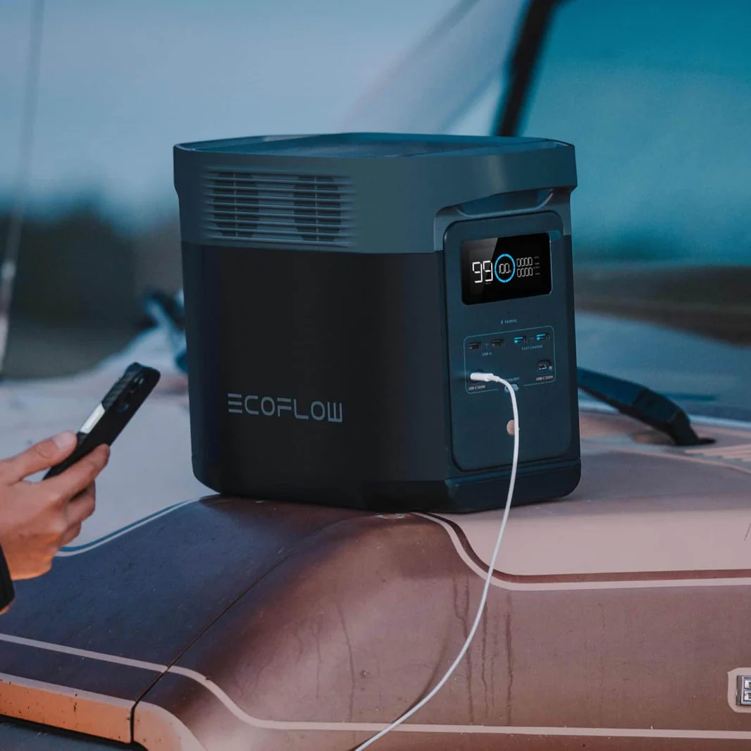Estación de energía EcoFlow Delta 2 sobre una furgoneta camper cargando un smartphone en exteriores.