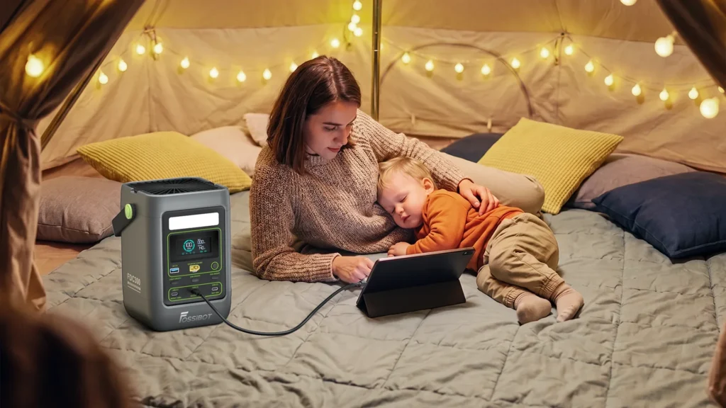 FOSSiBOT FDC300 cargando una tablet de forma silenciosa junto a un niño durmiendo en una tienda de campaña.